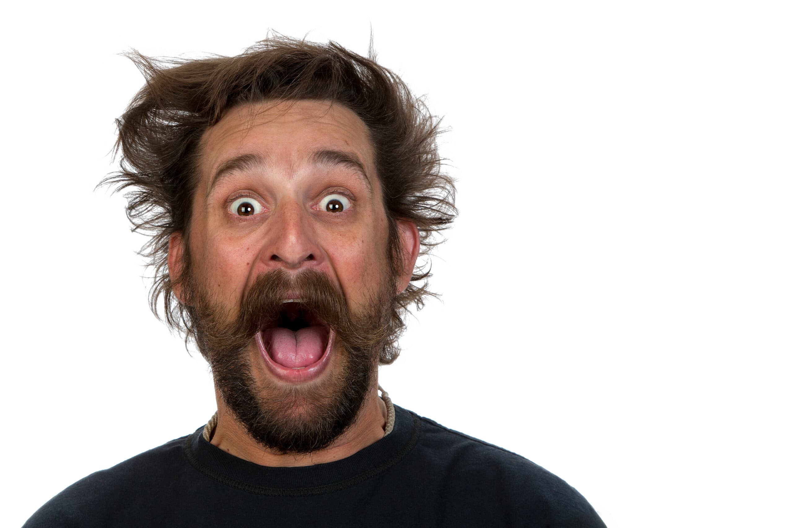 yell less as a parent A man with messy hair and a beard is wearing a dark shirt. He has a surprised expression, with wide eyes and mouth open, against a plain white background.